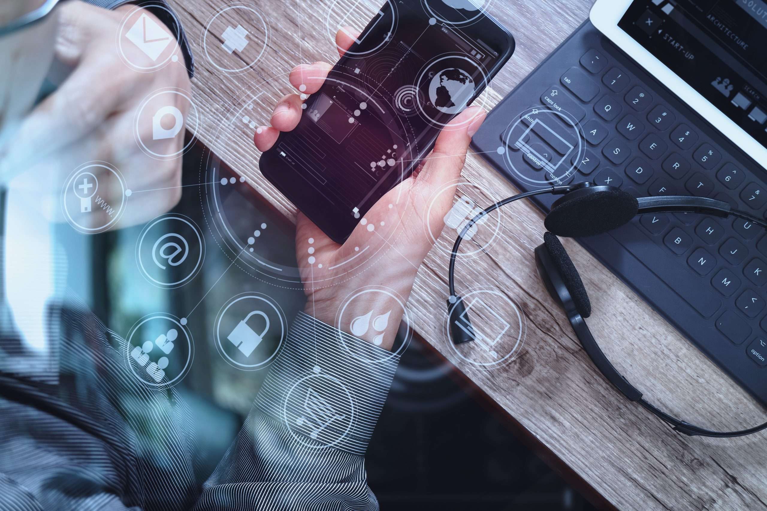Man with mobile phone and laptop in view and graphics to represent VoIP telephony solutions